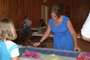 Youth are learning how to measure and cut fabric for their neck coolers with Monica Brinkley, County Extension Director and Agent in Liberty County