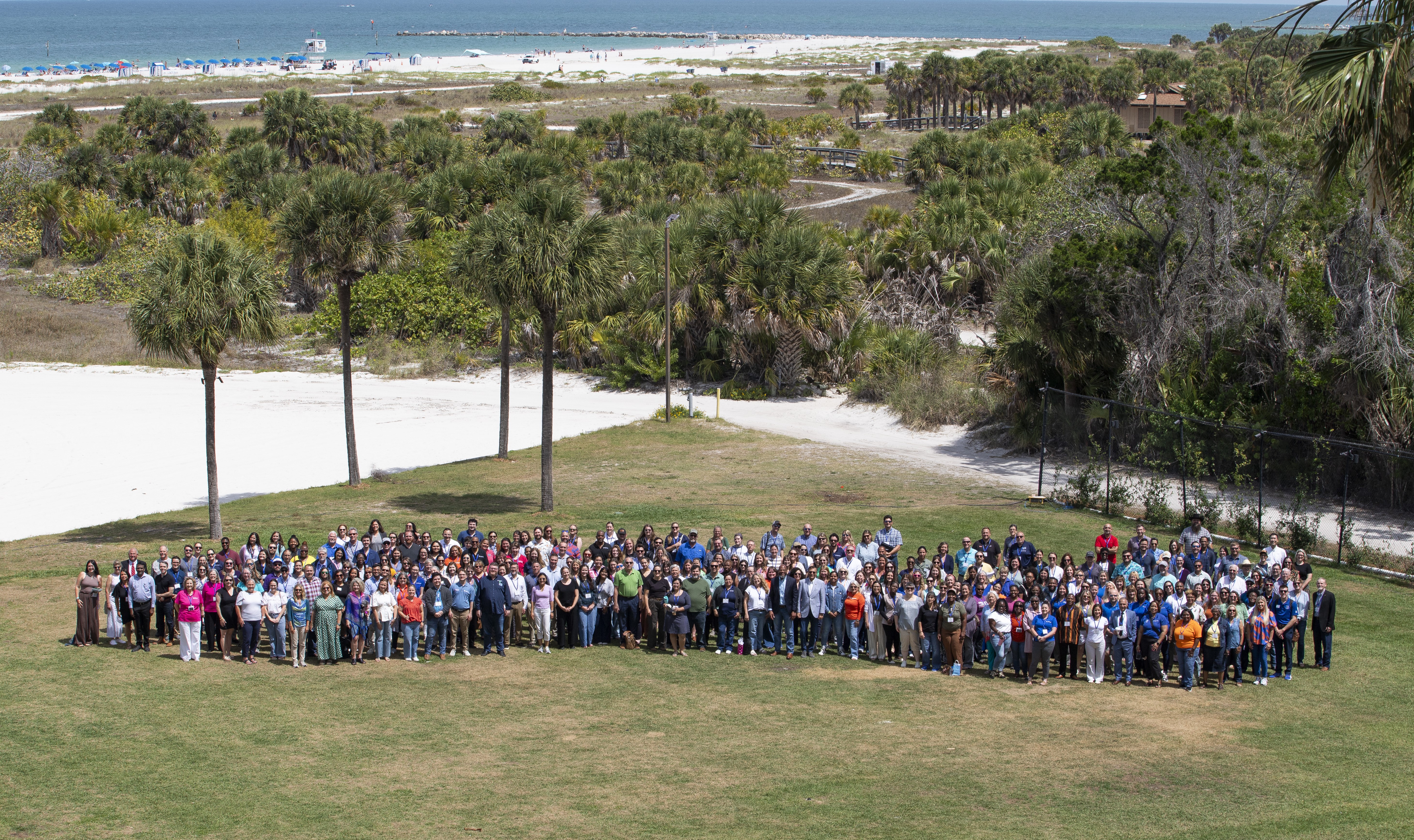 A large gathering of people on a lawn by the sea.